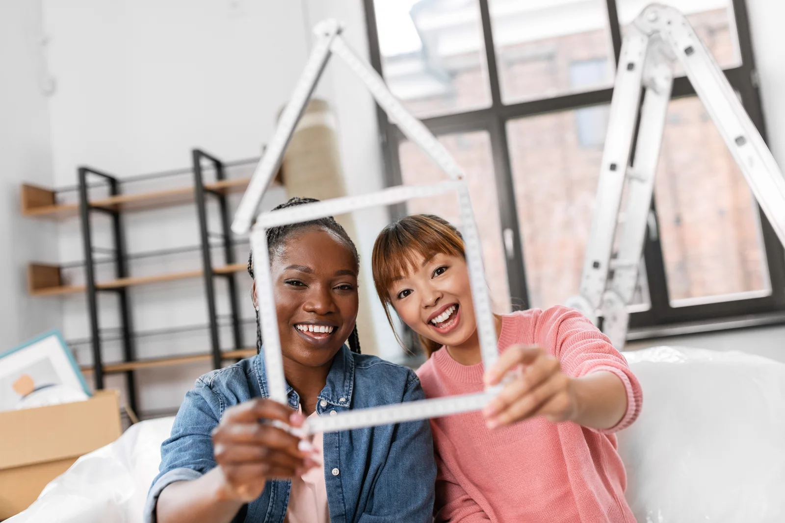 moving--people-and-real-estate-concept---happy-smiling-women-with-ruler-folded-in-shape-of-house-at-new-home--happy-smiling-women-with-ruler-in-shape-of-house-1766998947825.webp